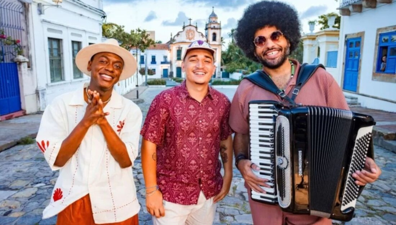 Jota.Pê, João Gomes e Mestrinho. Mestrinho segura a sanfona, eles estão nas ladeiras de Olinda, local onde foi gravado o projeto. Ao fundo, temos uma igreja